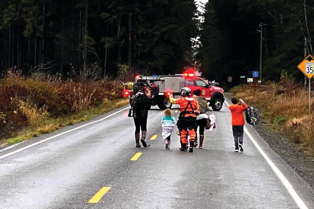 A Coast Guard rescue swimmer escorts multiple people who were evacuated from their residences during a flood near Forks on Monday, Nov. 15. The crew evacuated a total of 10 people, including several children, after receiving a request for assistance from Clallam County emergency responders.